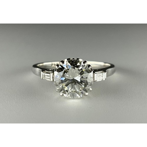 140 - A platinum solitaire diamond ring, with diamond set shoulders, set with an approx. 1.65ct round bril... 