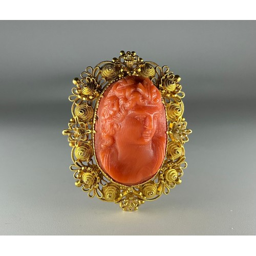 196 - An Antique tested 18ct gold mounted carved coral cameo brooch, the central carved orange coral cameo... 