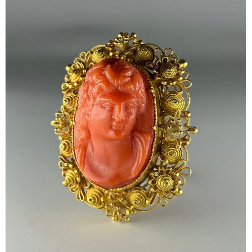 196 - An Antique tested 18ct gold mounted carved coral cameo brooch, the central carved orange coral cameo... 