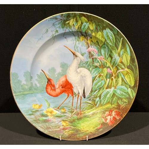 294 - A French Arts and Crafts period porcelain charger, hand painted, decorated with a pair of cranes ben... 