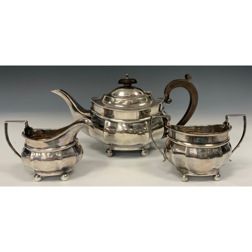 142 - A George V silver three piece tea set, ebony handled teapot, milk jug and sugar bowl, Cooper Brother... 