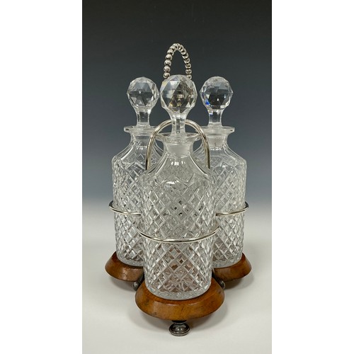 47 - An Edwardian oak and silver plated three bottle stand, with glass decanters, beaded looping handle, ... 