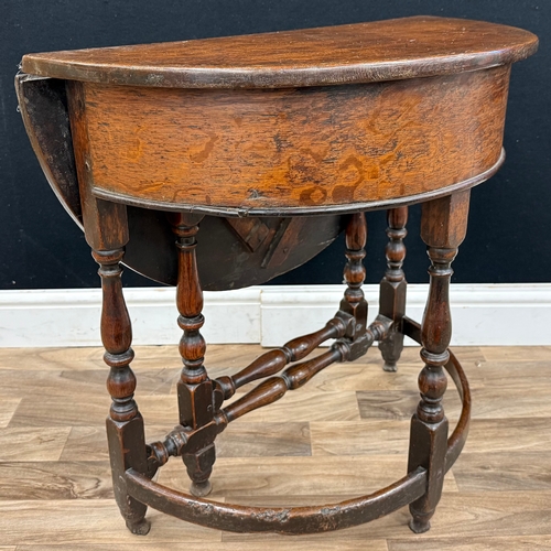 A late 17th century oak well table, hinged demi-lune top enclosing a ...