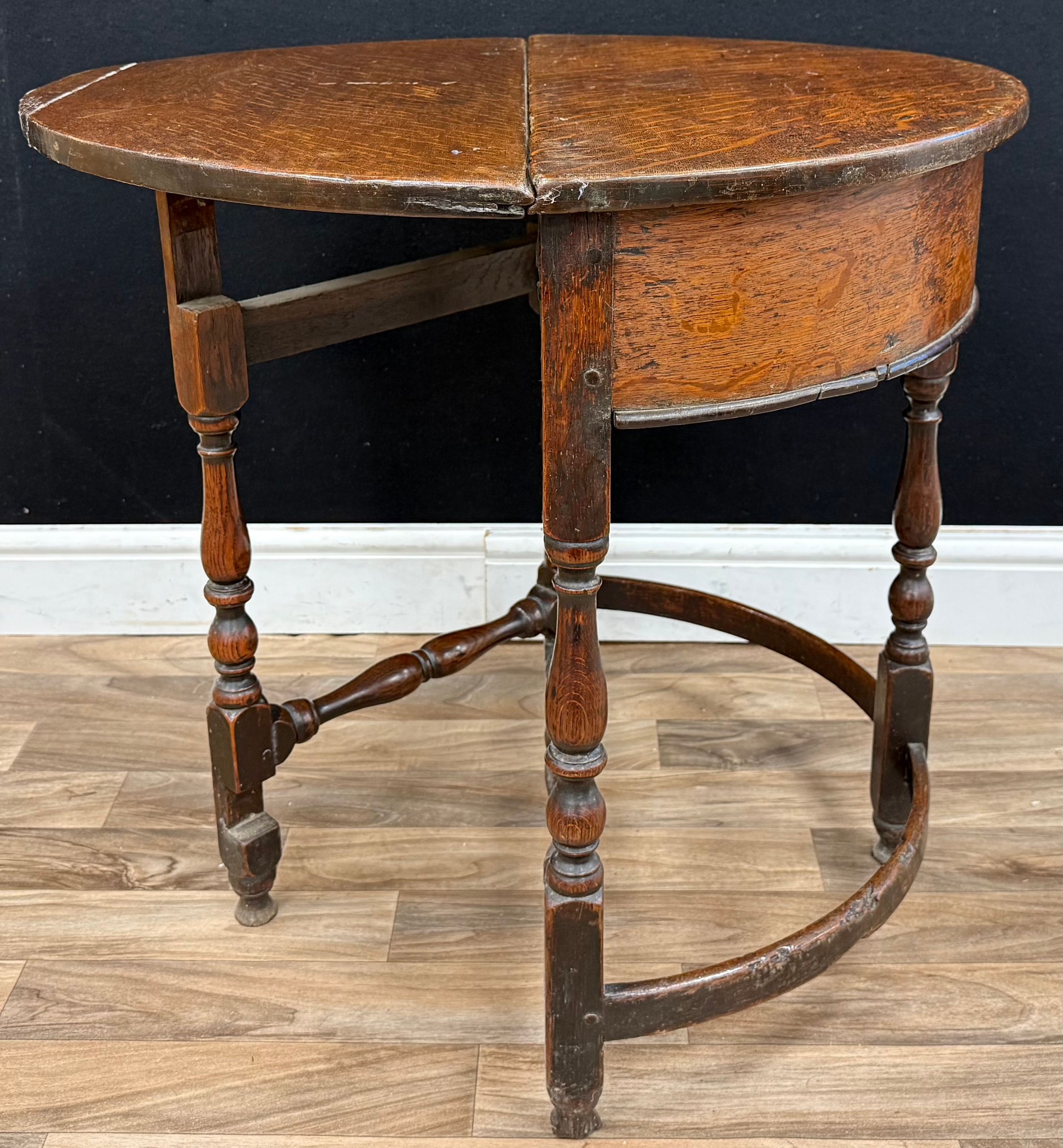 A late 17th century oak well table, hinged demi-lune top enclosing a ...