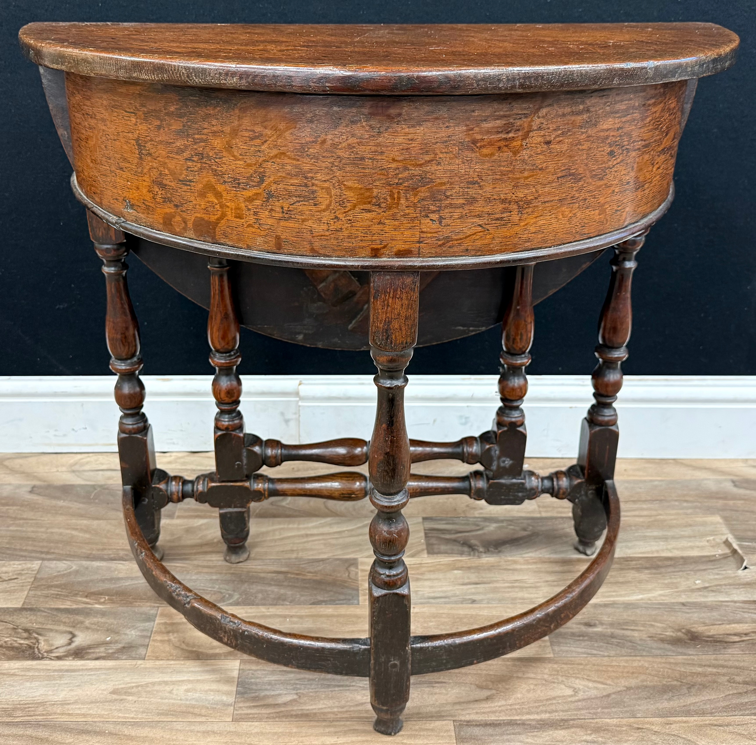 A late 17th century oak well table, hinged demi-lune top enclosing a ...