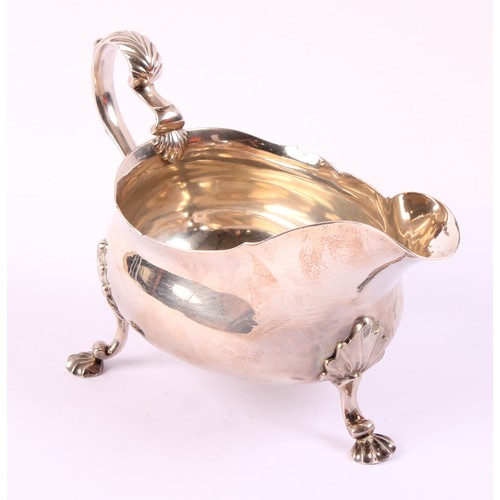 59 - A George II silver sauce boat, wavy rim, acanthus capped double-scroll handle, shell feet, 19cm long... 
