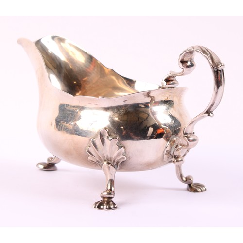 59 - A George II silver sauce boat, wavy rim, acanthus capped double-scroll handle, shell feet, 19cm long... 