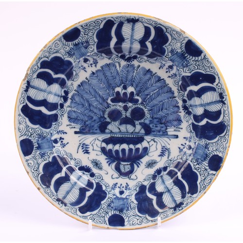 780 - A pair of 18th century Dutch Delft circular plates, painted in tones of blue with vases of flowers a... 