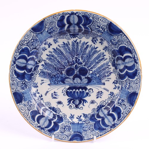780 - A pair of 18th century Dutch Delft circular plates, painted in tones of blue with vases of flowers a... 