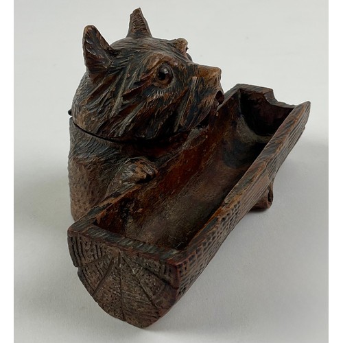 3000 - A Black Forest novelty inkwell, carved as a dog peering over a log, hinged cover, glass eyes, 12.5cm... 