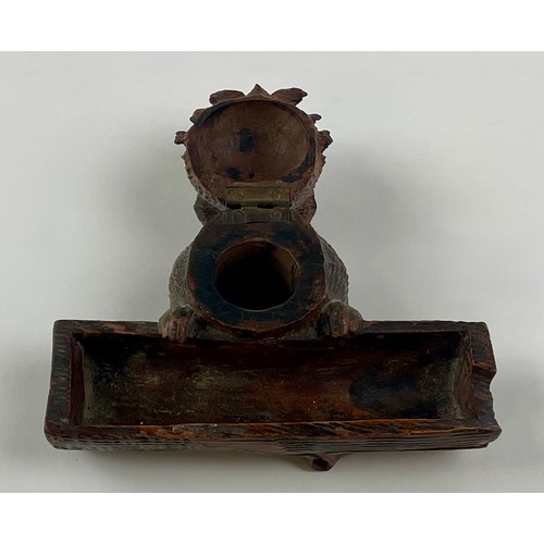 3000 - A Black Forest novelty inkwell, carved as a dog peering over a log, hinged cover, glass eyes, 12.5cm... 