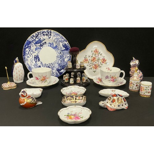 41 - Royal Crown Derby - a collection of fifteen thimbles on a two-tier pincushion stand; a penguin, tabb... 