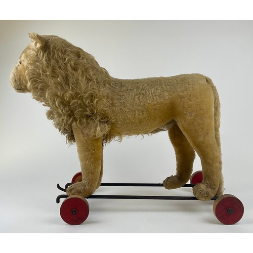 3056 - A 1920s Steiff lion on wheels, with blonde mohair, yellow and black glass eye, pink stitched nose, b... 