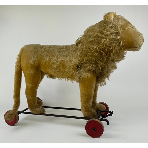 3056 - A 1920s Steiff lion on wheels, with blonde mohair, yellow and black glass eye, pink stitched nose, b... 
