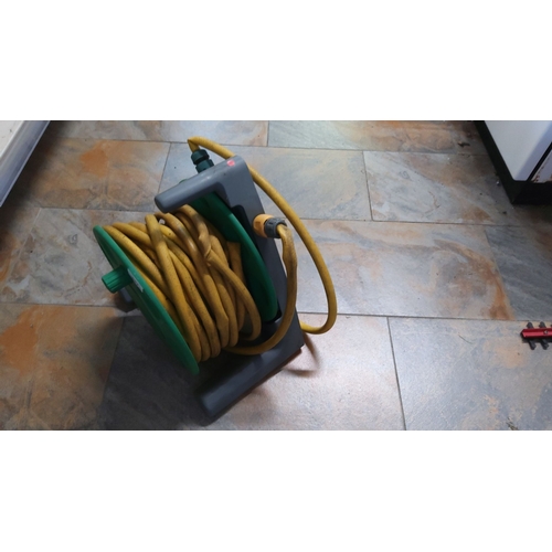 137 - Garden hose reel with a yellow hose, featuring a green and grey frame.