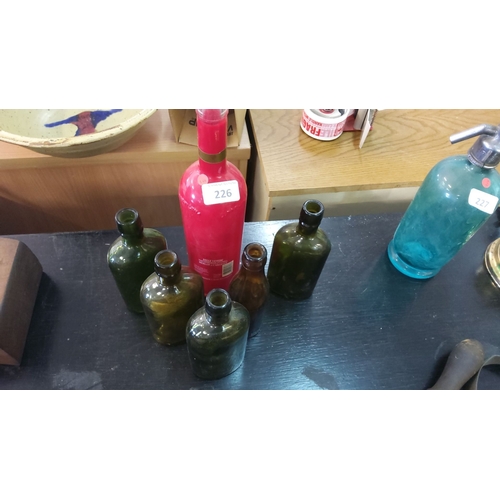 226 - Collection of six vintage glass bottles, including a red merlot bottle and five assorted green and b... 