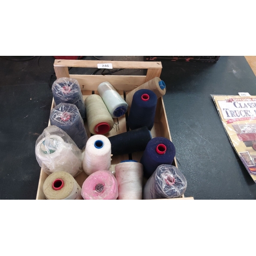 246 - Assorted lot of 13 spools of thread in various colors, including navy, white, pink, and beige.