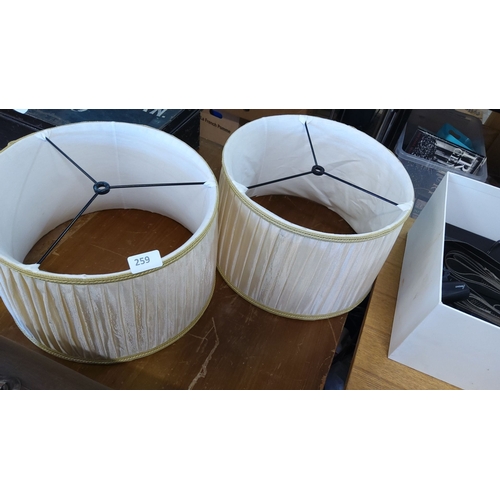 259 - Pair of cream drum lampshades with gold trim and supportive wire frame. Each lampshade measures appr... 