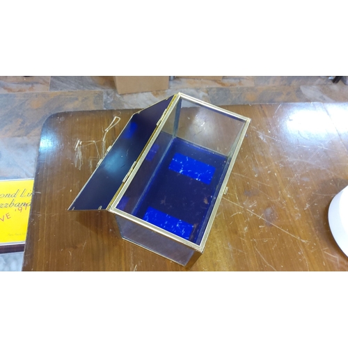 262 - Vintage glass display box with a blue interior and brass frame. Hinged glass lid with a clasp closur... 