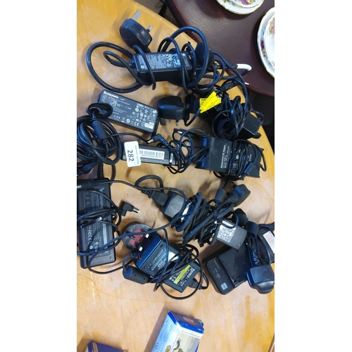 282 - Mixed lot of 12 various brand power adapters, including Lenovo, HP, and Kensington.