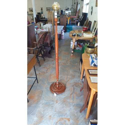 298 - Vintage wooden floor lamp featuring a turned spindle design, complete with a large spherical glass s... 