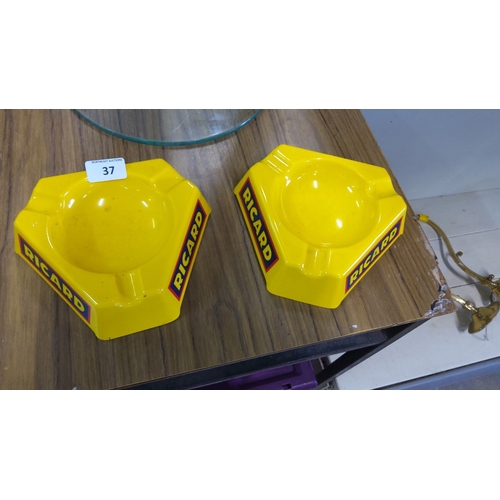 37 - Pair of vibrant yellow Ricard branded bakelite ashtrays with bold lettering.