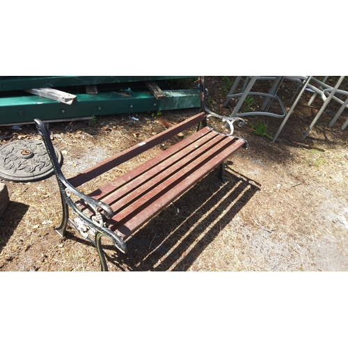 455 - Vintage metal and wood slatted garden bench with intricately designed iron armrests.