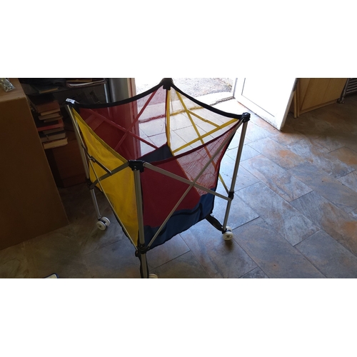 473 - Collapsible mesh storage basket with primary color panels and aluminum frame. The basket is on wheel... 