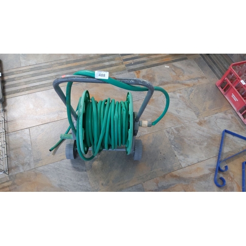 488 - Garden hose reel with green hose. Features a durable wheeled frame for easy transport and storage.