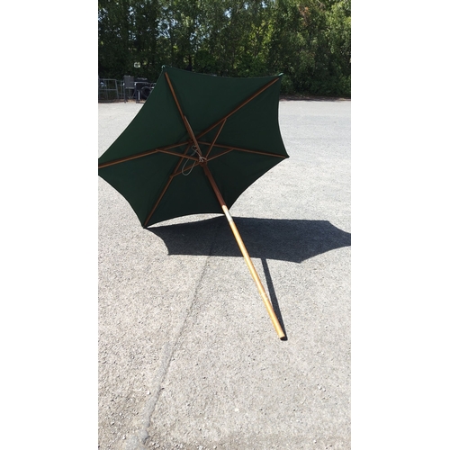 495 - Large green fabric patio umbrella with wooden pole and ribs. Sturdy construction.