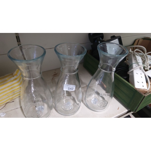 142 - Set of three clear glass carafes, each with 