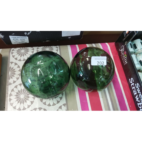 202 - Pair of emerald green glass spheres with marbled pattern and reflective surface. Each sphere measure... 