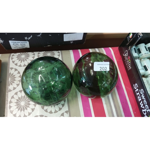 202 - Pair of emerald green glass spheres with marbled pattern and reflective surface. Each sphere measure... 