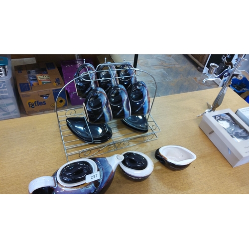 237 - Set of ceramic teapot, creamers, and cups with saucers. Glazed in blue, black, and white, displayed ... 