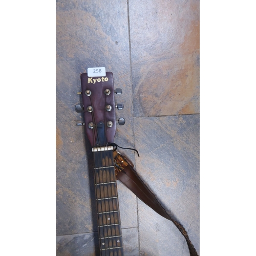 258 - Kyoto acoustic guitar with a natural wood finish, six strings, and adjustable brown strap. Brand log... 