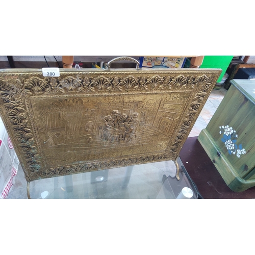 280 - Victorian brass fire screen featuring an ornate embossed scene of a domestic setting, framed with in... 