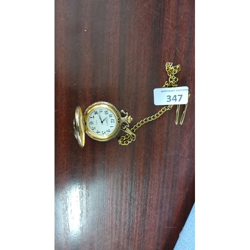 347 - Gold-tone commemorative pocket watch with chain. The front cover features a relief of the Titanic an... 