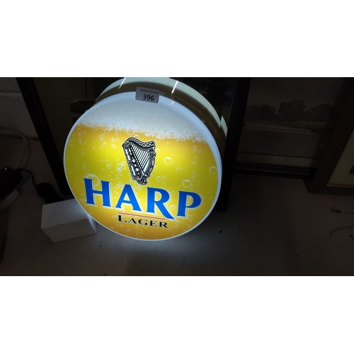 396 - Illuminated Harp Lager sign featuring iconic logo and frothy beer design. Showcases classic brewery ... 