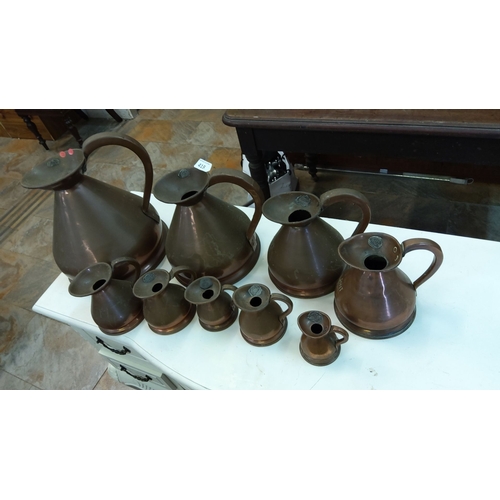 415 - Set of nine vintage copper graduating measuring jugs from 1 gallon to 1/8 gill