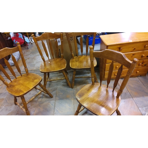 419 - Set of four wooden spindle-back chairs in light oak finish, featuring turned legs and a classic desi... 