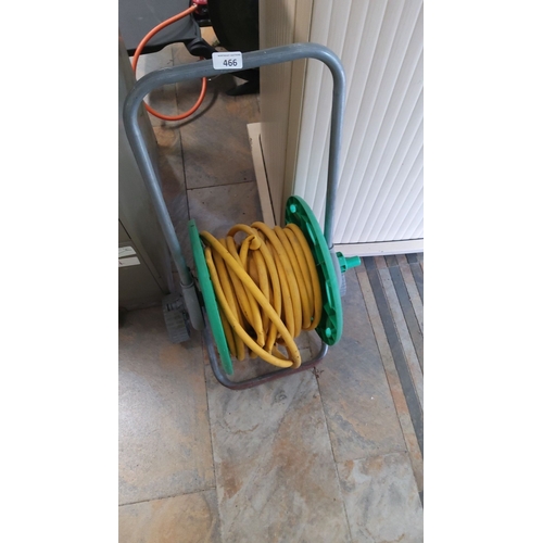 466 - Garden hose reel with yellow hose. Constructed from green and gray plastic. 4 Designed with a portab... 