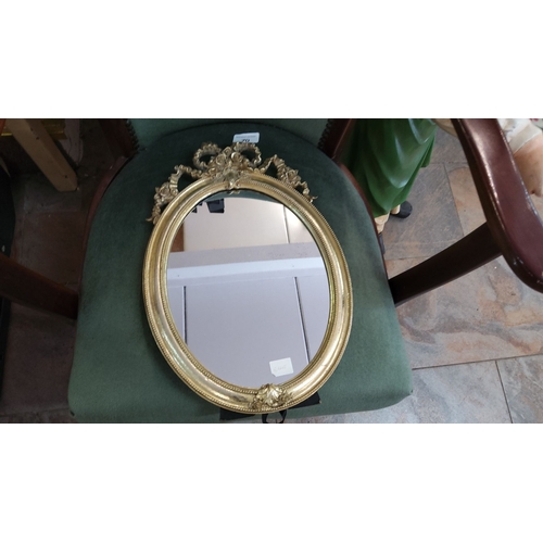 70 - Oval gold-framed free standing mirror with ornate rococo-style floral detailing at the top.