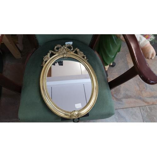 70 - Oval gold-framed free standing mirror with ornate rococo-style floral detailing at the top.