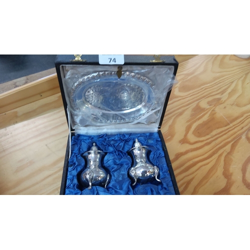 74 - Sterling silver boxed set featuring a pair of salt and pepper shakers and an engraved oval dish.