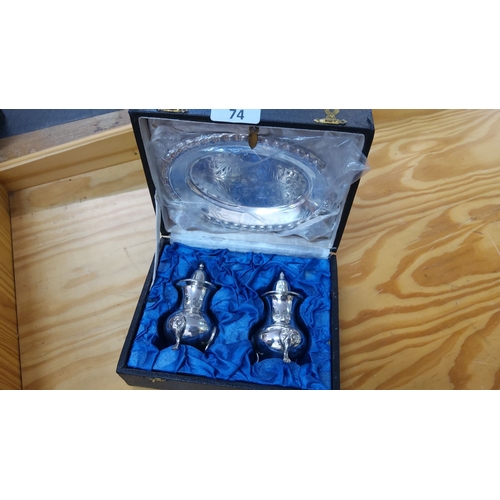 74 - Sterling silver boxed set featuring a pair of salt and pepper shakers and an engraved oval dish.
