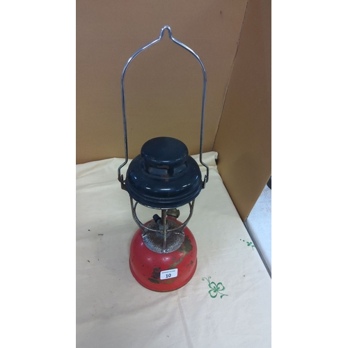 10 - Vintage red and black metal kerosene lantern with a wire handle, industrial design.