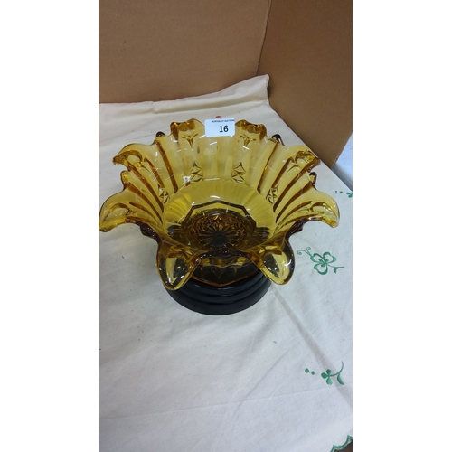 16 - Amber glass bowl with ruffled edges, featuring cut glass designs, accompanied by a separate black di... 