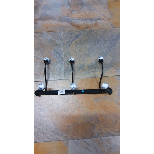 175 - Black metal coat rack with 3 decorative ceramic hooks featuring blue floral patterns.