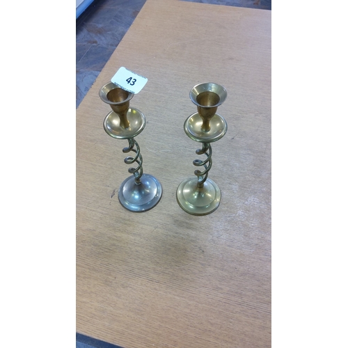 43 - Pair of brass candlesticks with spiral stems and round bases, classic design.