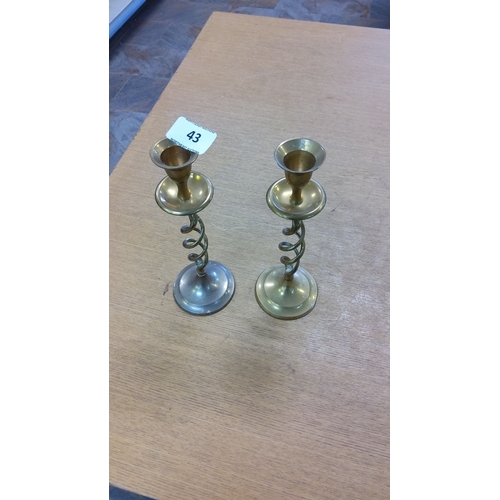 43 - Pair of brass candlesticks with spiral stems and round bases, classic design.